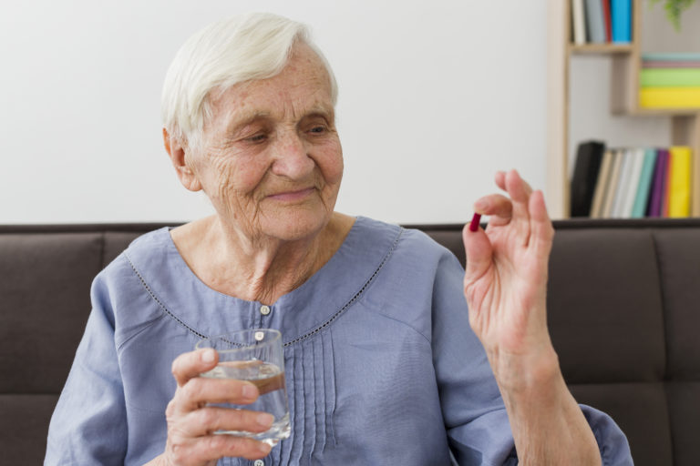 front-view-elder-woman-taking-her-daily-pill