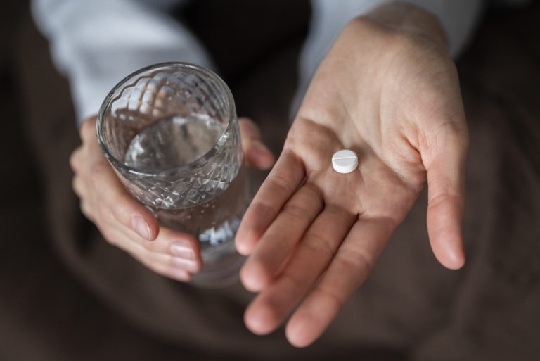 close-up-hands-holding-pill-glass